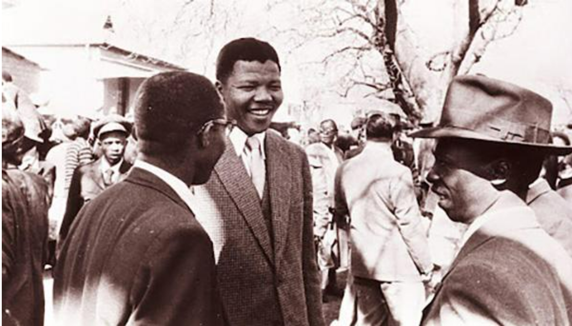 Nelson Mandela speaking with co-defendants outside the “Treason Trial” in South Africa in the late 1950s. [Source: axios.com]